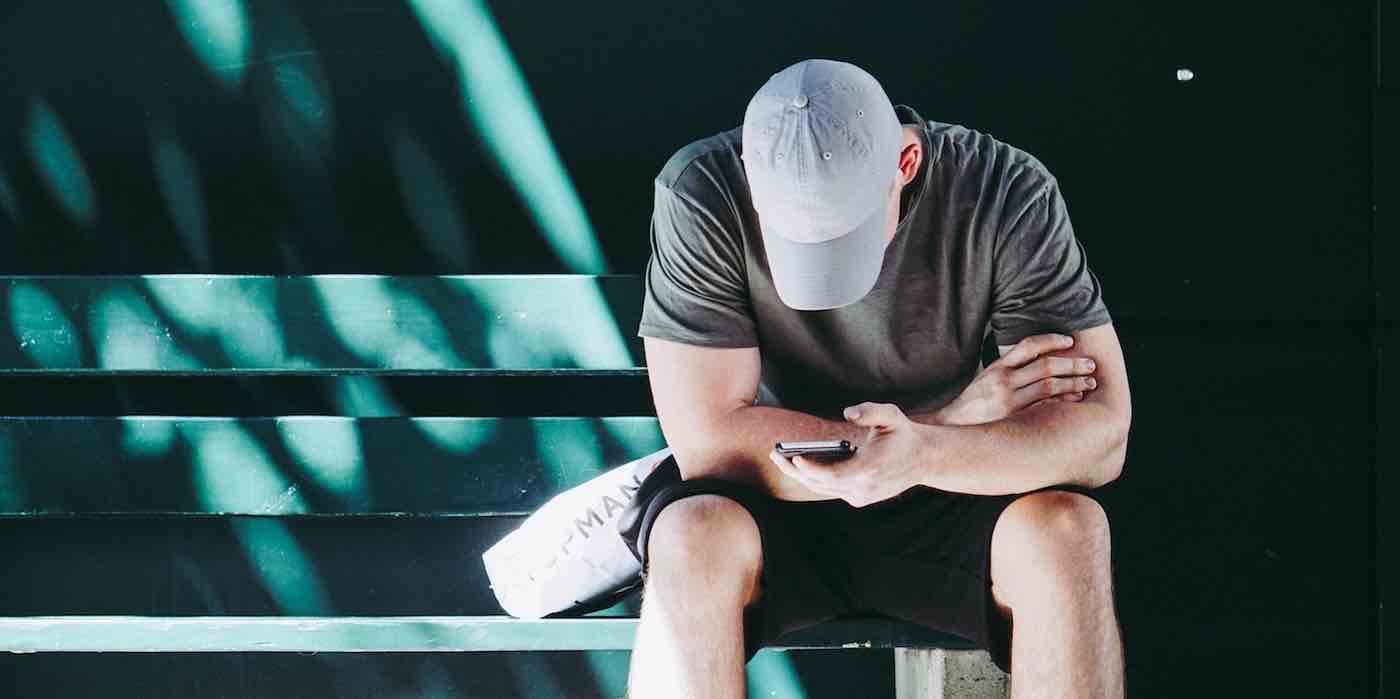 Person with cell phone sitting on bench 