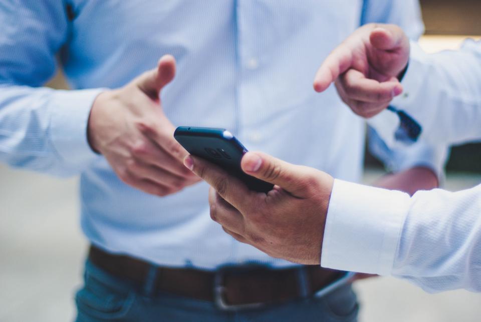 Two people pointing to and discussing cell phone