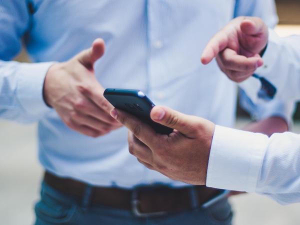 Two people pointing to and discussing cell phone 