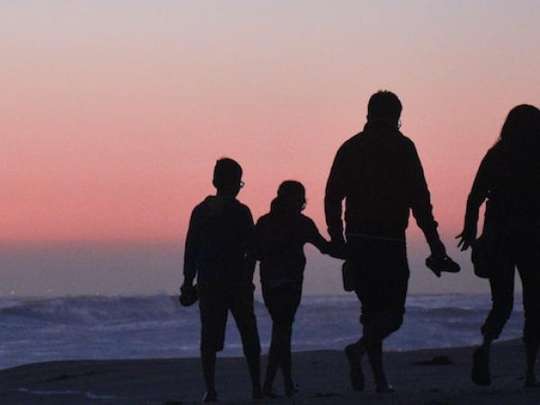 Family walking on beach at sunset