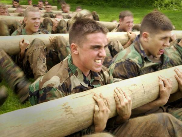 men in military uniforms holding logs to exercise 