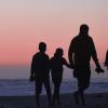 Family walking on beach at sunset