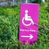 Purple disability placard in grass shows outline of person in wheelchair 